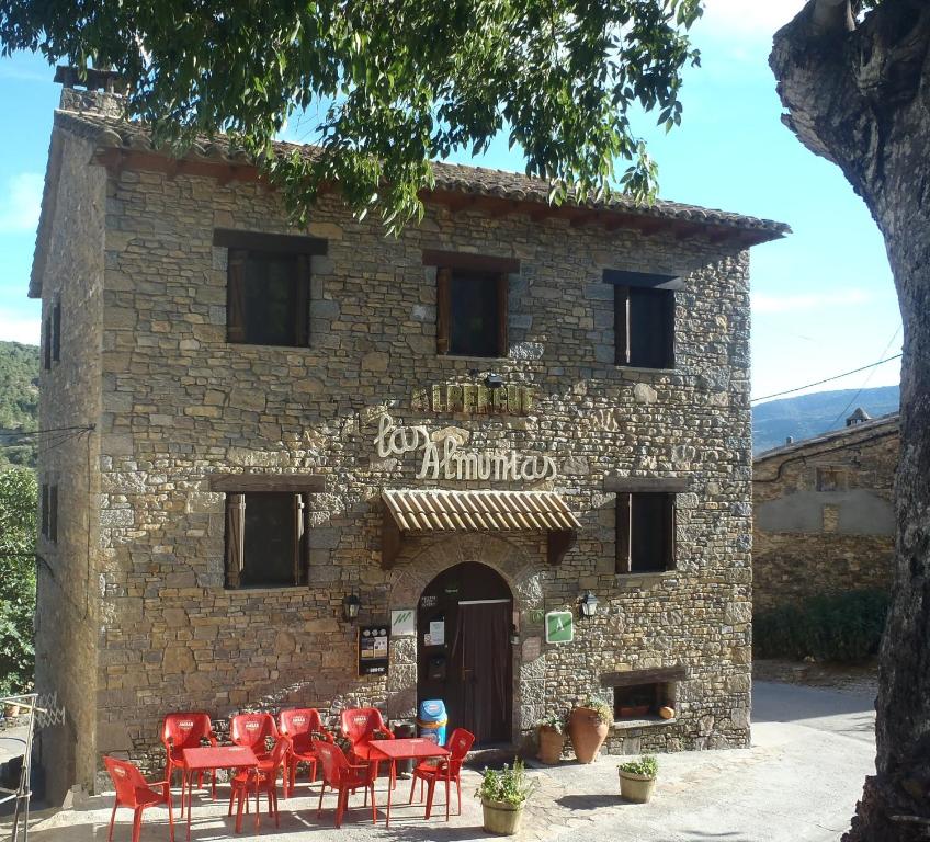 un edificio con mesas rojas y sillas delante de él en Albergue Las Almunias, en Las Almunias