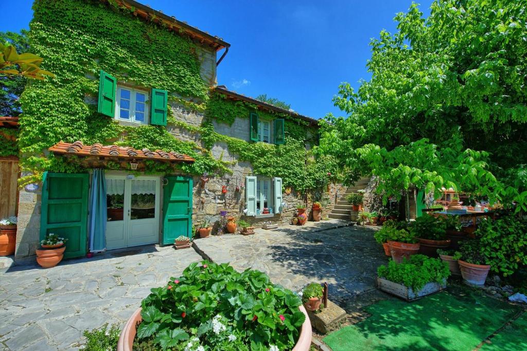 une maison avec des portes vertes et des plantes dans une cour dans l'établissement Casale San Martino by PosarelliVillas, à Cortone