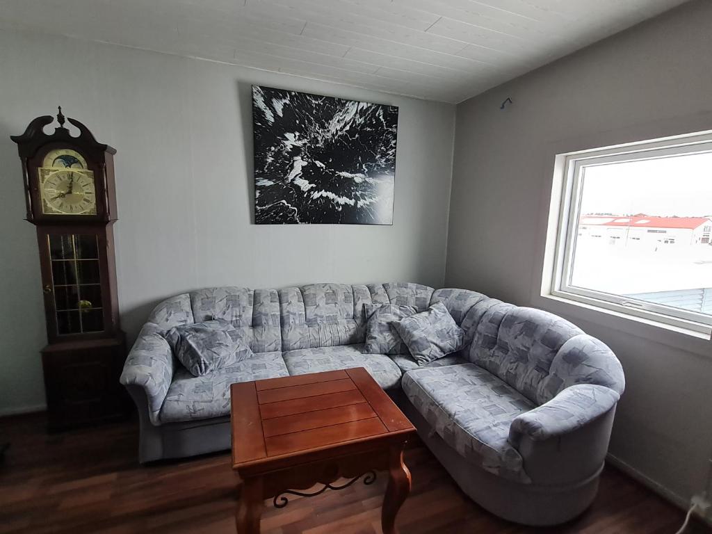 a living room with a couch and a clock at MB Guesthouse in Grímsnes og Grafningshreppur