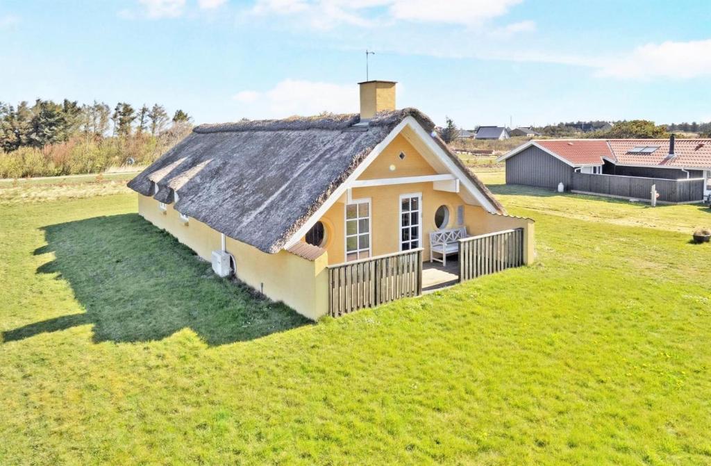 una pequeña casa con techo en un campo de césped en Viking Surf Cottage, en Klitmøller