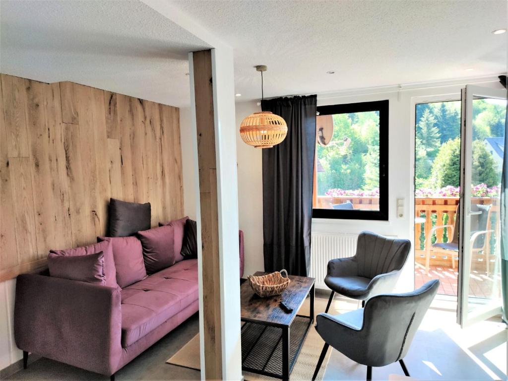 sala de estar con sofá rosa y 2 sillas en Pfefferstübchen Ferienwohnung Schanzenblick, en Brotterode