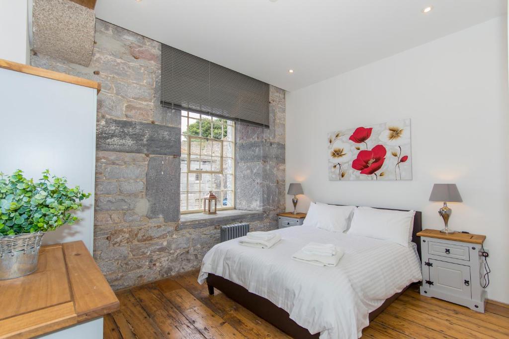 een slaapkamer met een bed en een bakstenen muur bij PureServiced Royal William Yard in Plymouth