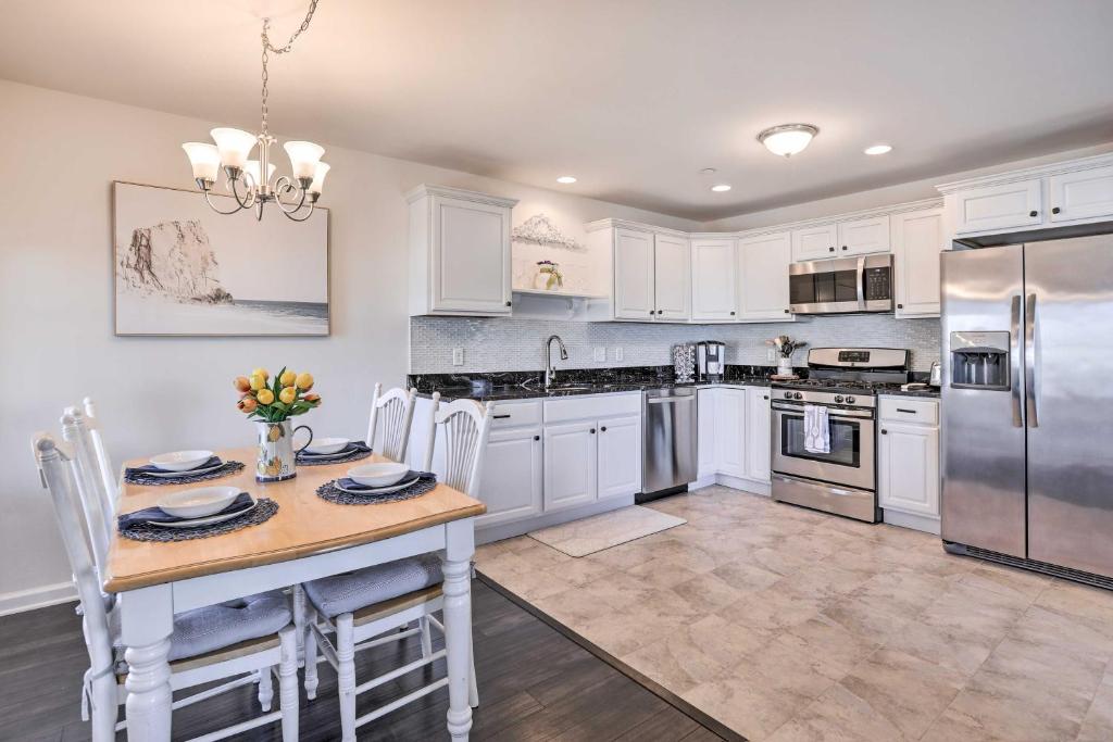 a kitchen with white cabinets and a table with chairs at Bright and Airy Condo - Walk to Ortley Beach! in Seaside Heights