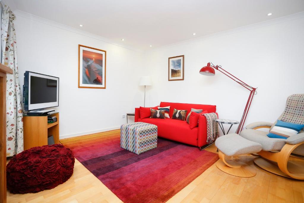 a living room with a red couch and a chair at Edinburgh Mews Apartment in Edinburgh