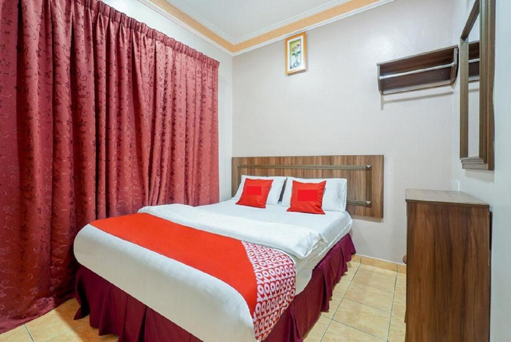 Schlafzimmer mit einem großen Bett und roten Vorhängen in der Unterkunft Hill Times Inn Hotel in Ipoh