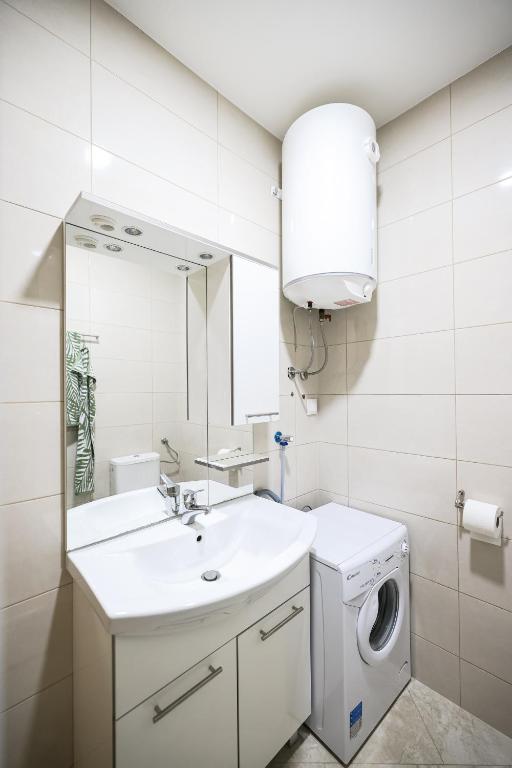a bathroom with a sink and a washing machine at Apartments Anka with Seaview in Vrsi