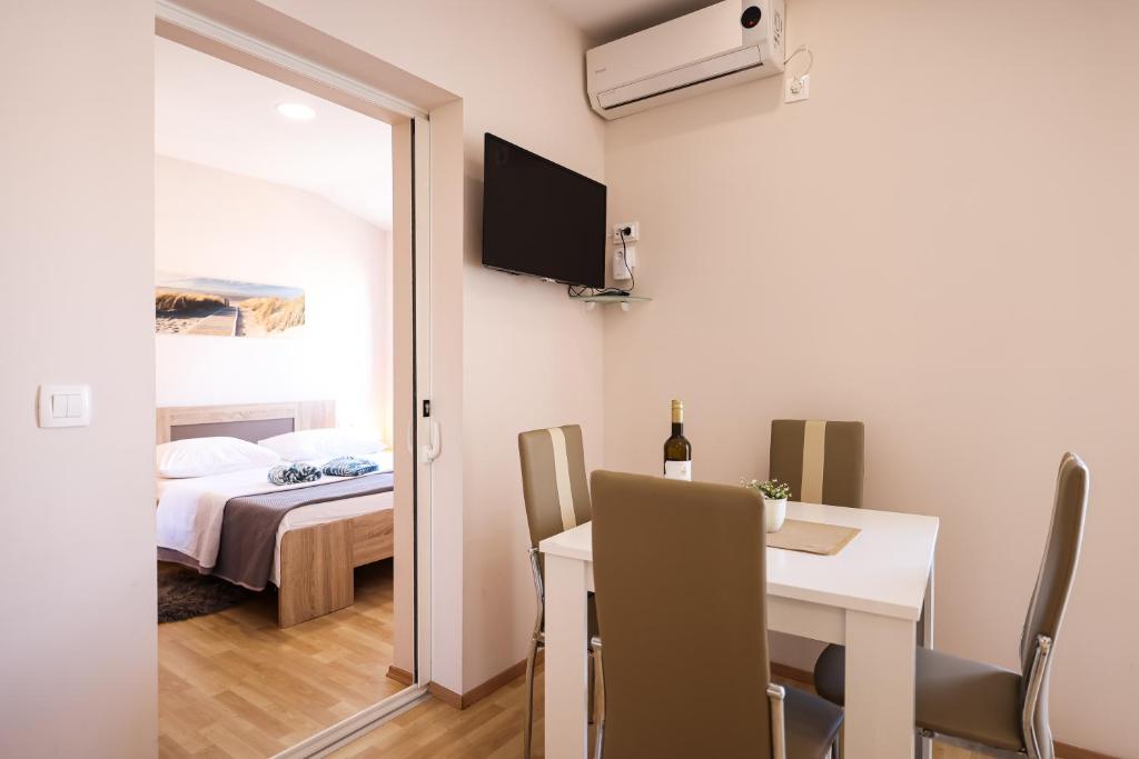 a room with a table and a bed and a room with a window at Apartments Anka with Seaview in Vrsi