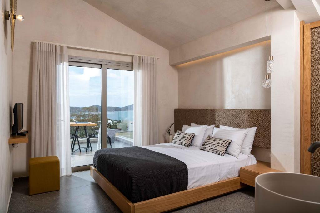 a bedroom with a large bed and a balcony at The Olive Tree Villa Elounda in Elounda
