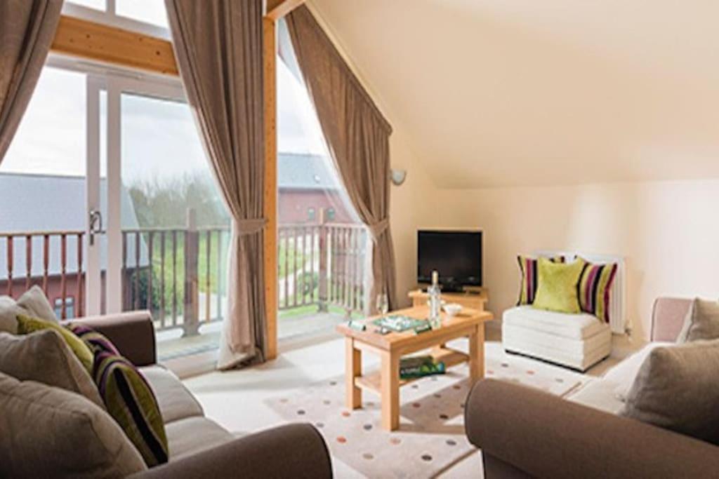 a living room with a couch and a table at Puffin Hot tub Lodge, 4 bedrooms Resort, Pool,Gym,Bar in Padstow