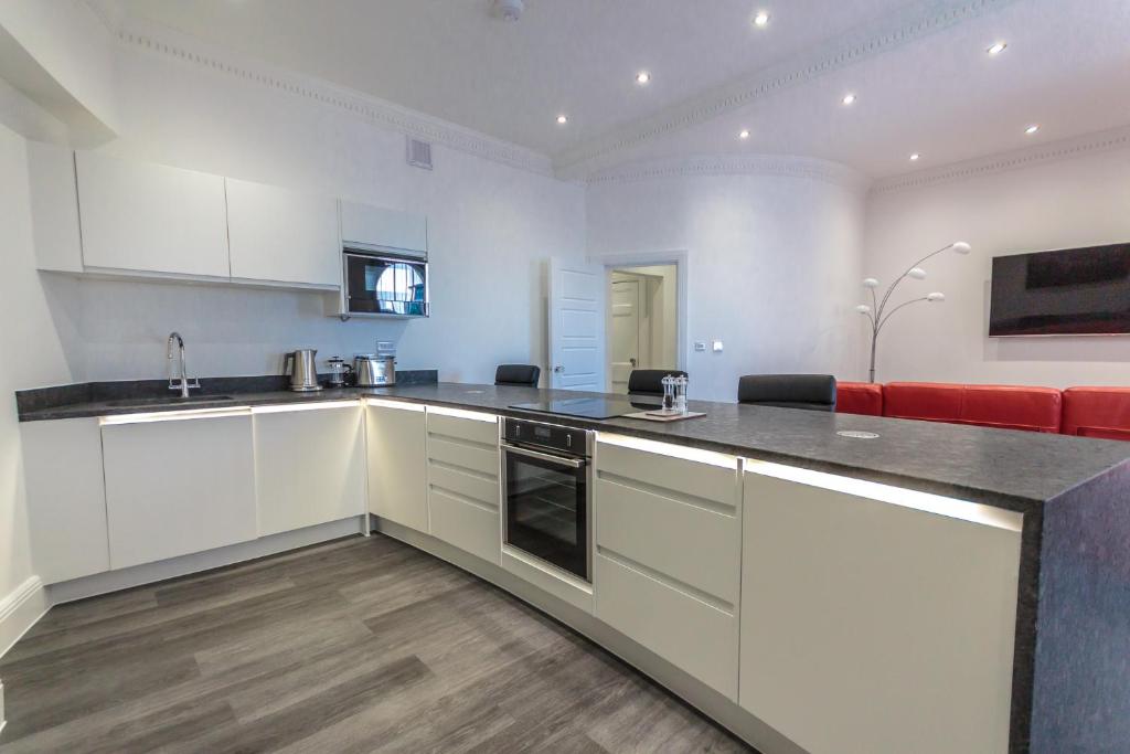 a kitchen with white cabinets and a red couch at The Balmoral Suite in Plymouth