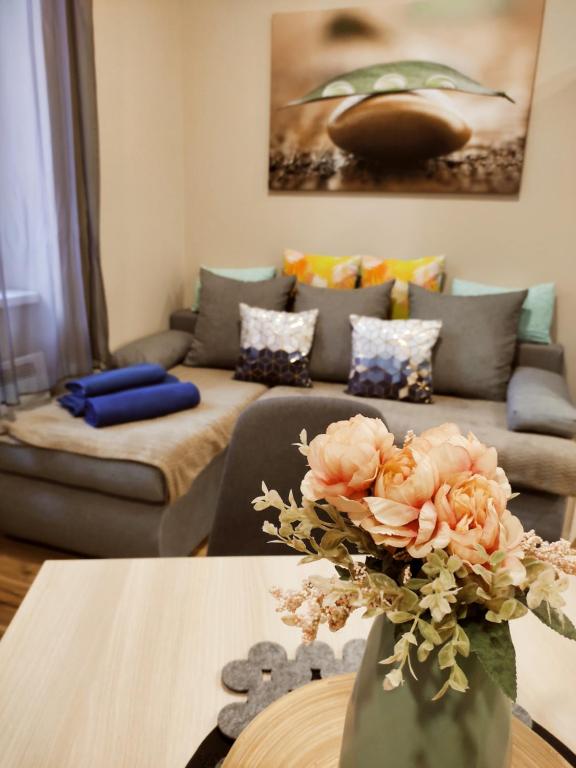 a living room with a couch and a vase with flowers at FAND Center Apartman in Szeged