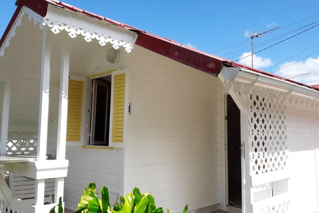 a white house with yellow shutters at Bungalow d'une chambre avec jardin clos et wifi a Fort de France in Fort-de-France