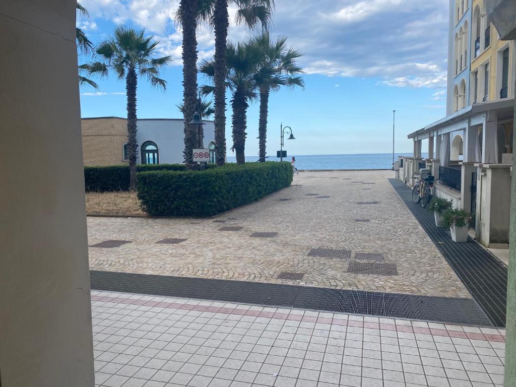 a sidewalk with palm trees and the ocean in the background at Brezza Marina in Porto Recanati