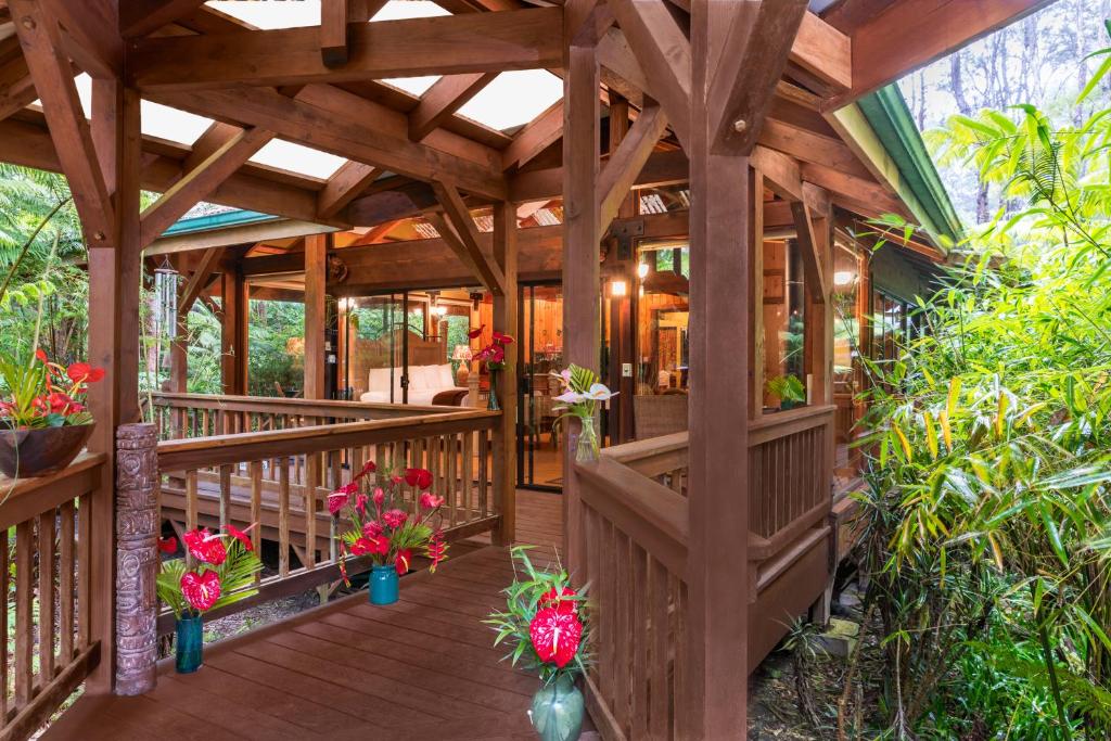 a wooden pergola with flowers on a deck at Volcano Village Lodge in Volcano