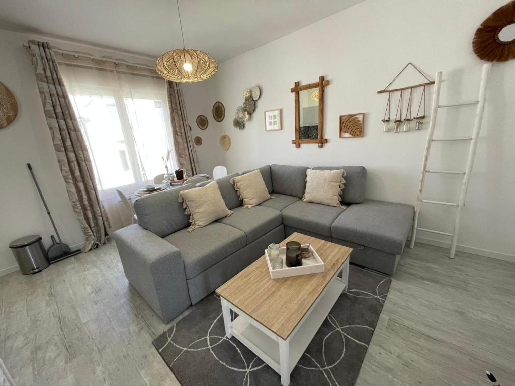 a living room with a gray couch and a table at Le Bohème - Centre Ville, Netflix et WIFI, parking, idéal familles, couples et voyages d'affaire in Niort