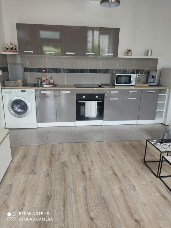 a kitchen with stainless steel appliances and wooden floors at Apt lumineux in Gonesse