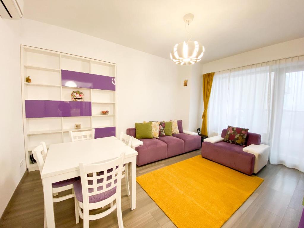 uma sala de estar com uma mesa e um sofá roxo em VR2 Central Apartment em Bucareste