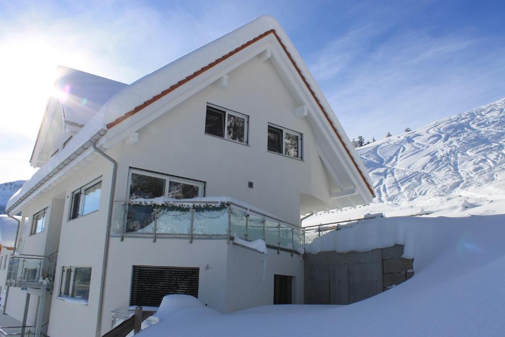 una casa en la nieve con una montaña en el fondo en Moderne 3-Zimmerwohnung, an Skipiste, mit Aussicht, en Flumserberg