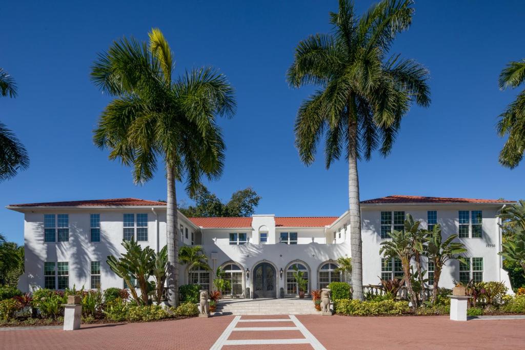 a large white building with palm trees at Shangri-La Springs in Bonita Springs