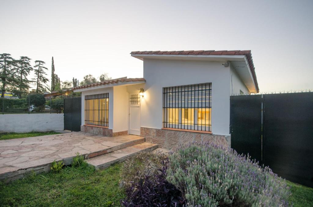 a white house with a black fence at Casa en Villa Carlos Paz con Pileta , Quincho y Jardín a Pasos del Centro in Villa Carlos Paz