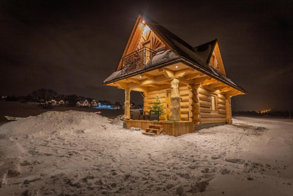 una baita di tronchi nella neve di notte di Domek Mietusiowa Pchełka a Poronin