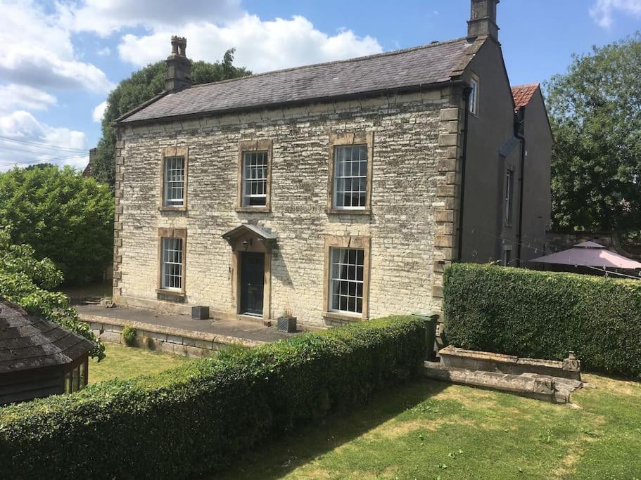 una vieja casa de piedra con un seto delante de ella en The Hole in the Wall, Midsomer Norton, Nr Bath & Longleat en Bath