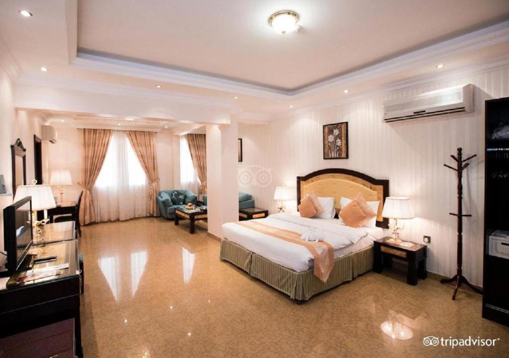 a bedroom with a large bed and a living room at Garden Hotel Muscat By Royal Titan Group in Muscat