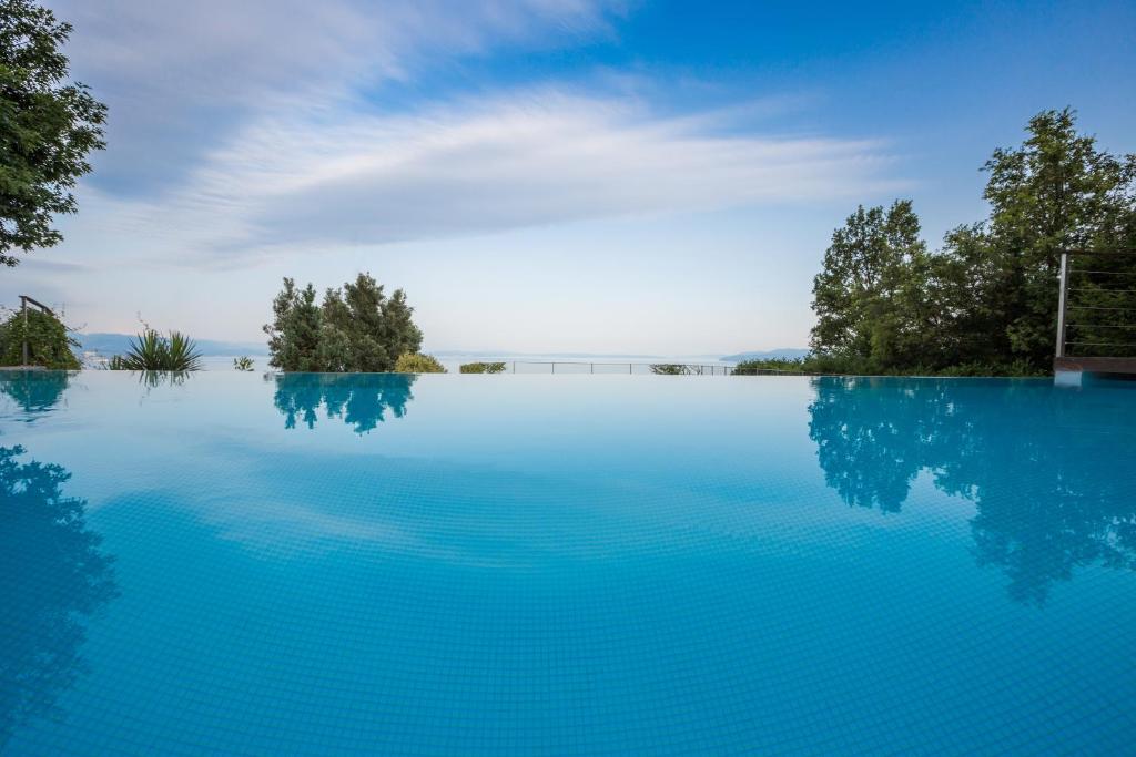 a pool of blue water with trees in the background at Villa Opatija Hills in Matulji