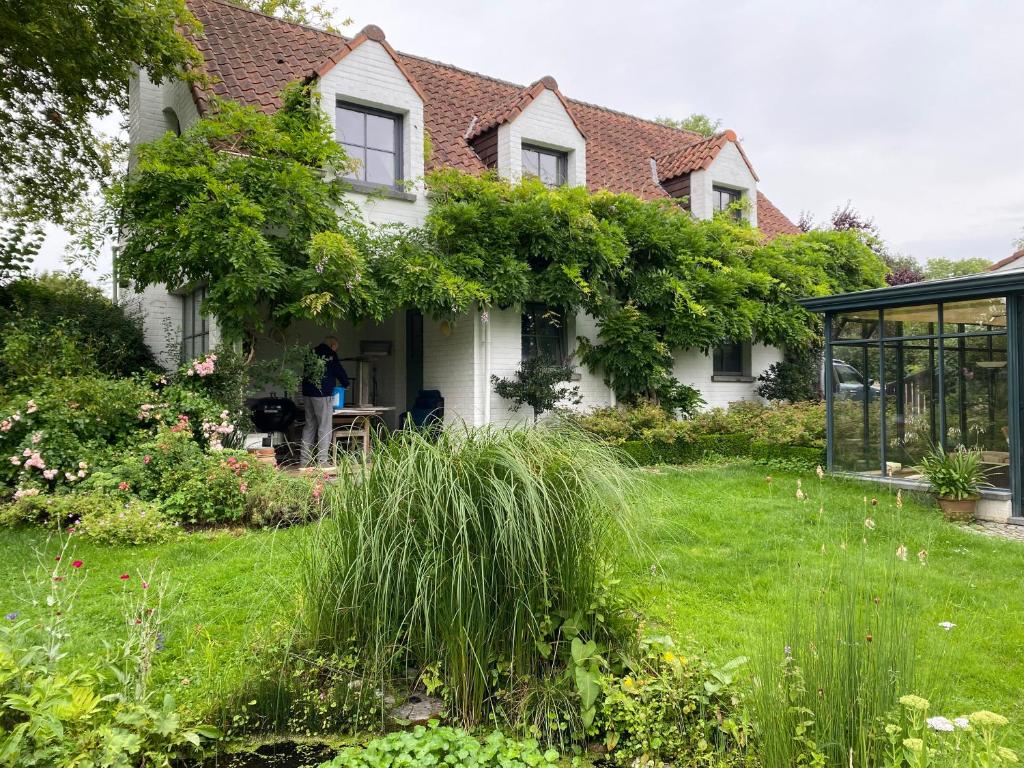 une personne debout à l'extérieur d'une maison avec un jardin dans l'établissement Le Cottage, à Lasne