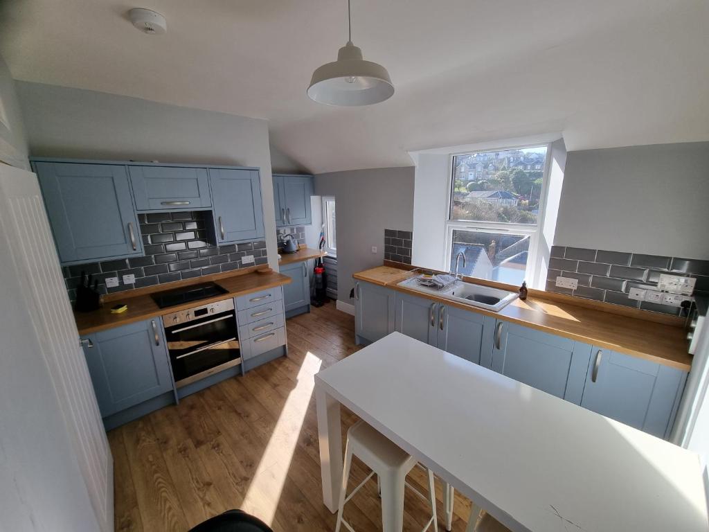 a kitchen with blue cabinets and a table in it at No7 Oban Harbour in Oban