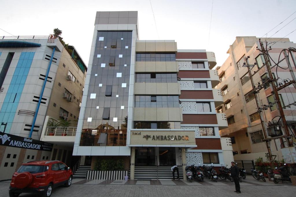 een hoog gebouw met een auto ervoor geparkeerd bij Hotel Ambassador in Indore