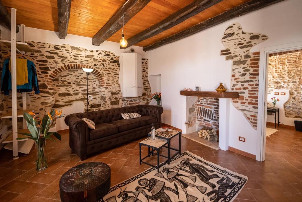 sala de estar con sofá y pared de piedra en Cascina Fogona - Sport e Natura en Altare