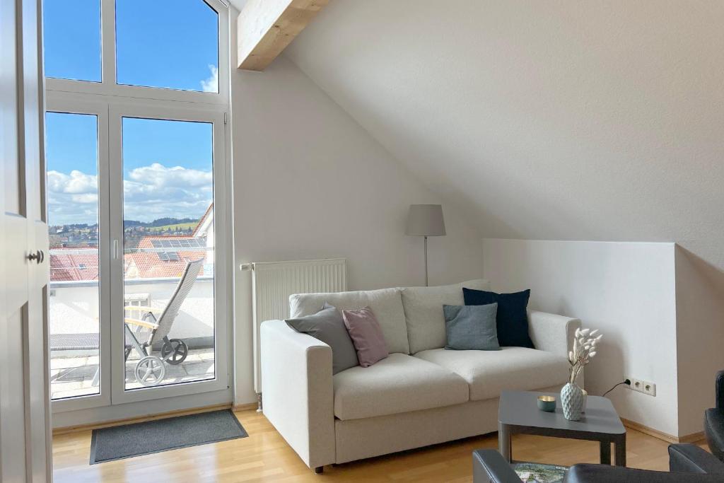 a living room with a couch and a large window at Apartment mit Dachterrasse & Sauna in Wangen im Allgäu