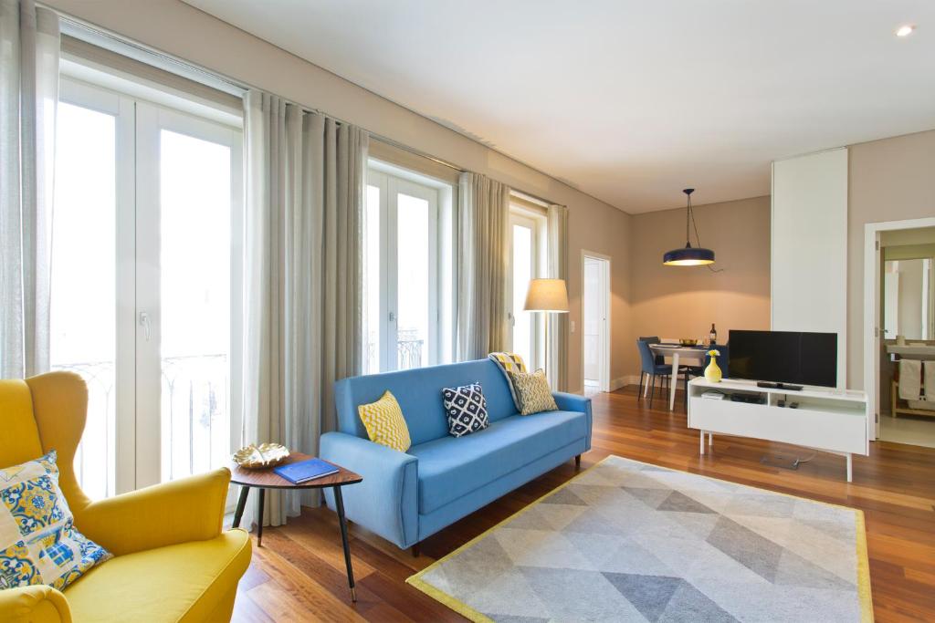 a living room with a blue couch and a tv at Cardosas Square Luxury Apartments by Porto City Hosts in Porto