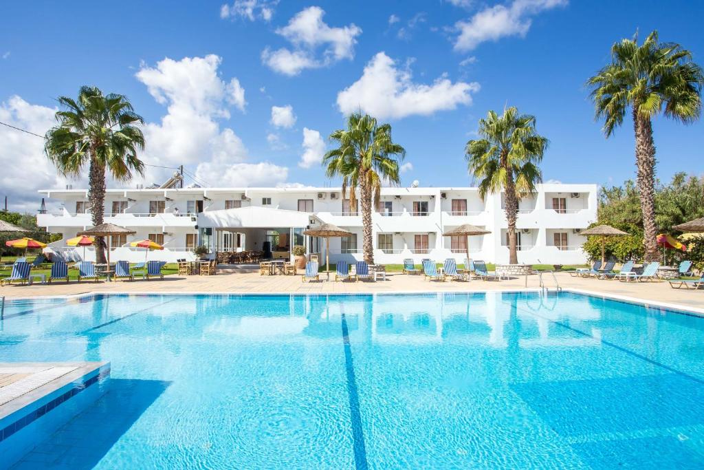 uma piscina com palmeiras e um hotel ao fundo em Sam's Studios em Faliraki