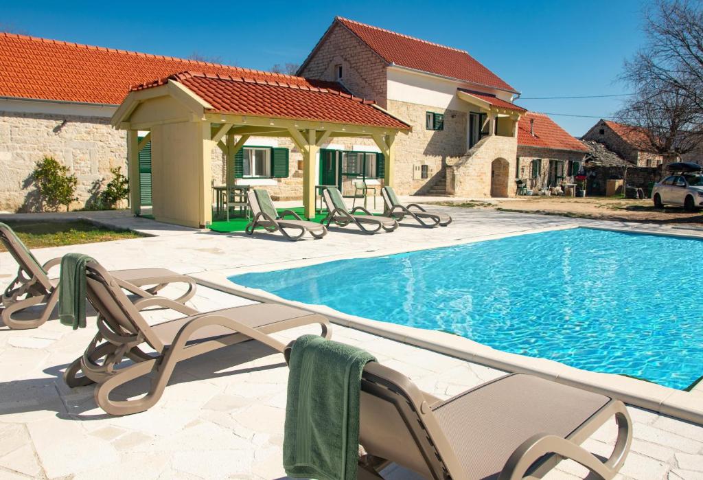 uma piscina com cadeiras ao lado de uma casa em Rural Villa Olive Krka- 30 min from sea coast,private pool, free parking, wifi, family friendly, National park Krka 10 min em Ljubotić