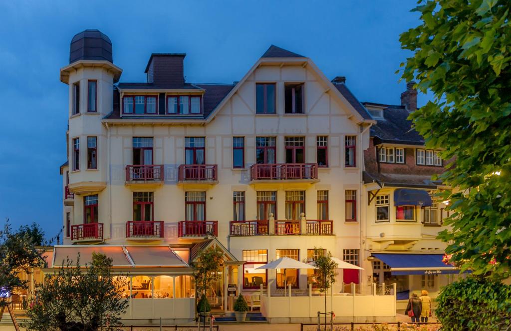 un gran edificio blanco con balcones rojos en Hotel Heritage, en De Haan