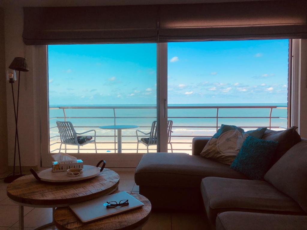 ein Wohnzimmer mit Couch und Blick aufs Meer in der Unterkunft MIRAMAR Zeedijk 168 Blankenberge in Blankenberge