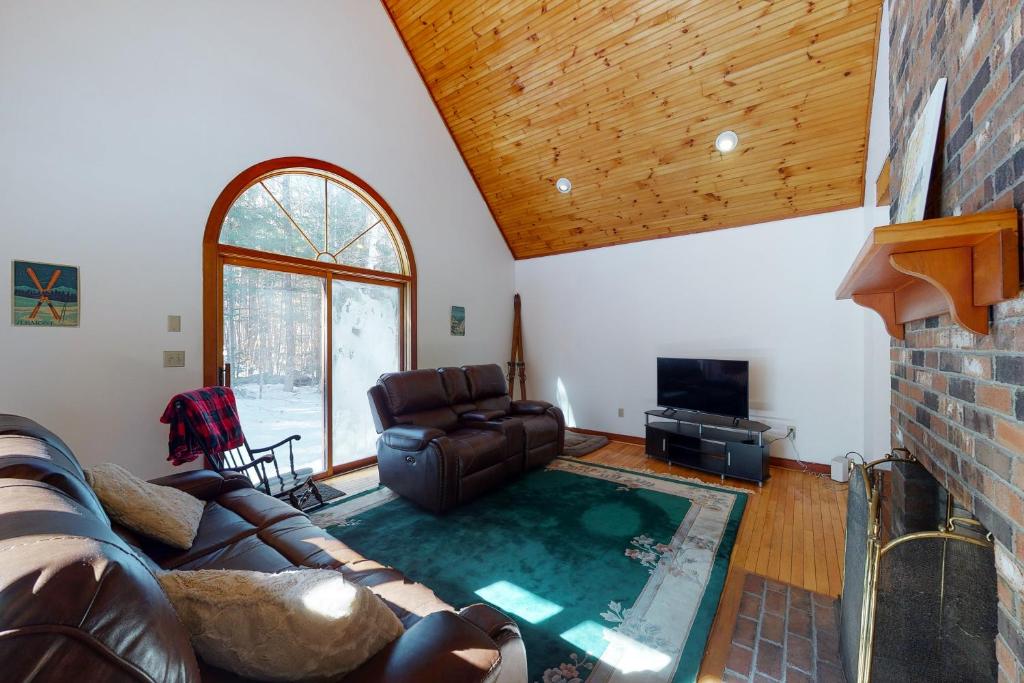 a living room with a leather couch and a fireplace at Cozy Cabin in the Woods in Londonderry