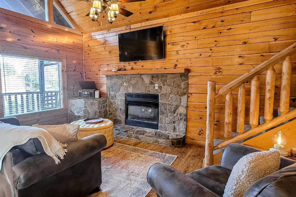 a living room with a stone fireplace in a log cabin at Parton Ways in Pigeon Forge