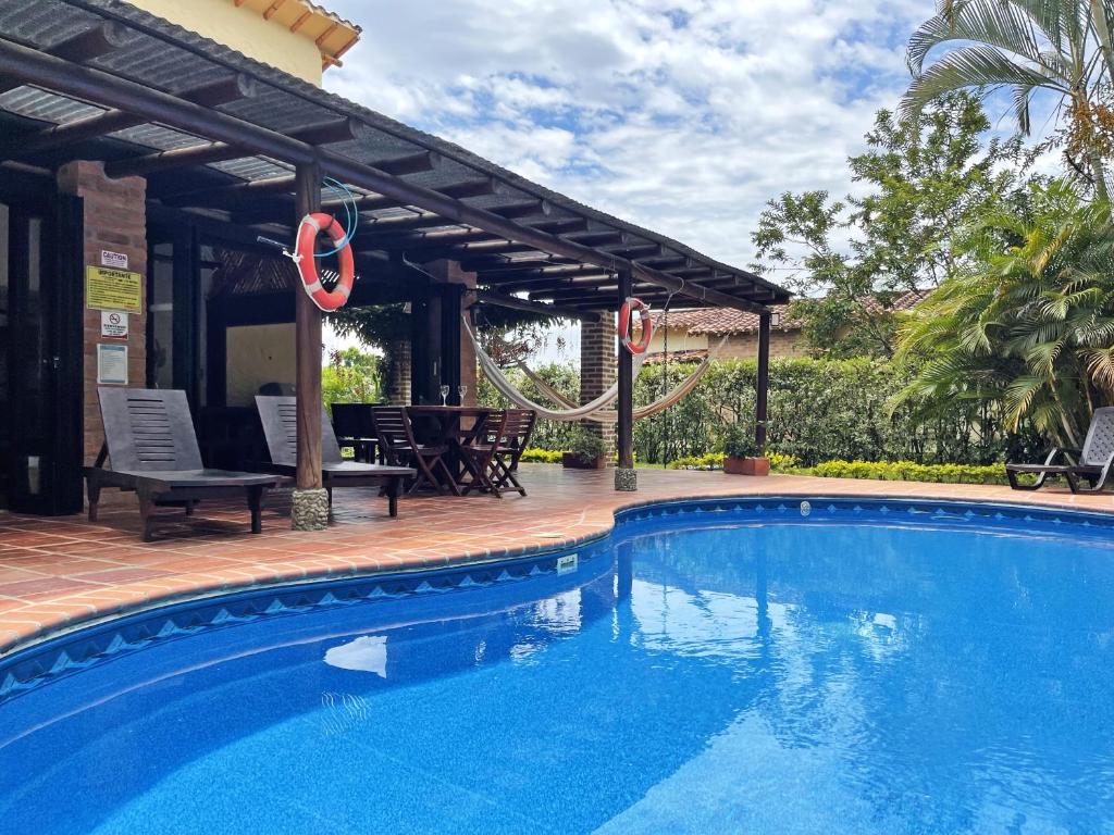 uma piscina com uma pérgula ao lado de uma casa em Fincas Panaca HERRERÍA 7 Grupo VIP em Quimbaya