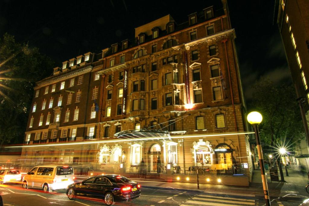 duży budynek z samochodami zaparkowanymi przed nim w obiekcie Ambassadors Bloomsbury w Londynie