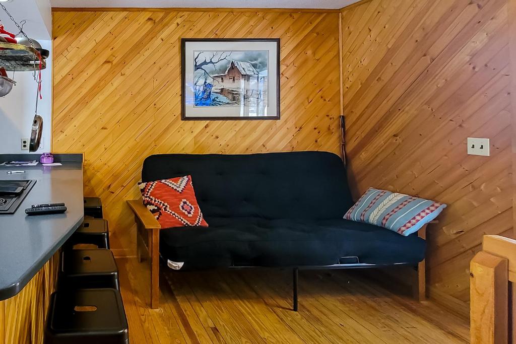 ein schwarzes Sofa in einem Zimmer mit einer Holzwand in der Unterkunft Mountain Memories in Gatlinburg