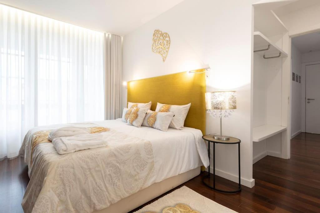 um quarto com uma cama grande e uma cabeceira amarela em Apartamento Avenida em Viana do Castelo