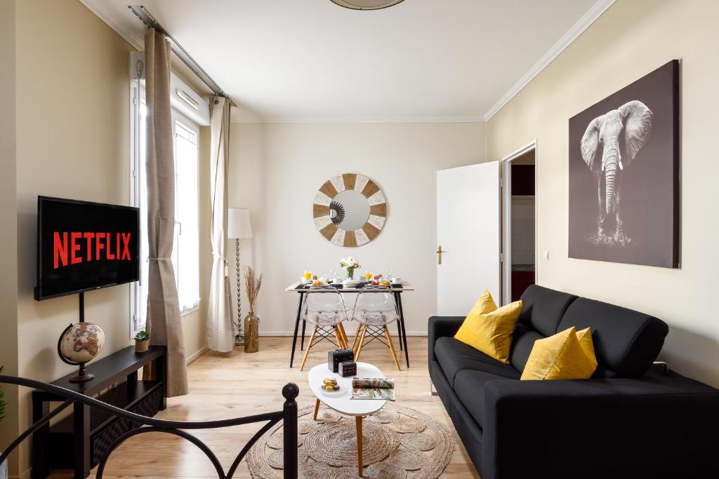 a living room with a black couch and a table at Cocoon 2 Proche - Disney Paris- Parking gratuit in Serris