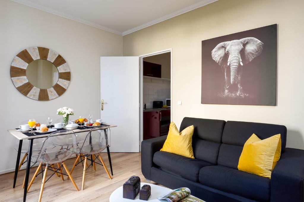 a living room with a blue couch and an elephant painting at Cocoon 2 Proche - Disney Paris- Parking gratuit in Serris
