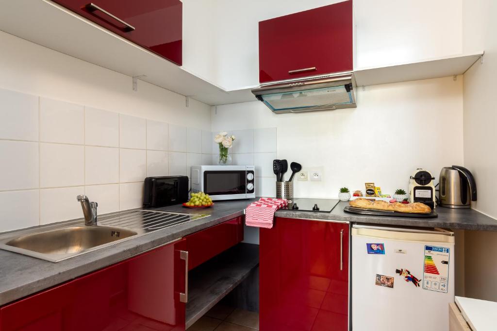 a small kitchen with red cabinets and a sink at Cocoon 2 Proche - Disney Paris- Parking gratuit in Serris