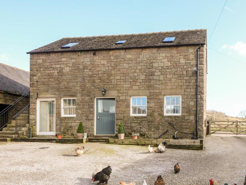 a brick house with chickens in front of it at Gratton Grange Farm- The Cottage in Bakewell