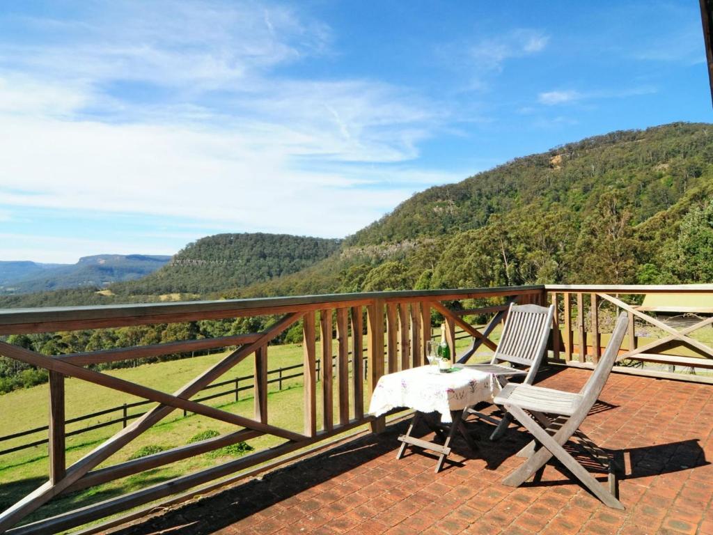 un tavolo e 2 sedie su un balcone con vista sulle montagne di Alcheringa Cottage Amazing Location with views a Kangaroo Valley