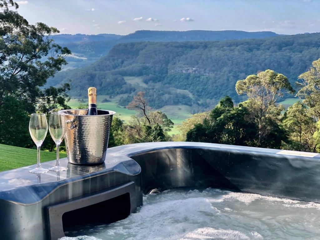 - un bain à remous avec une bouteille de vin et des verres dans l'établissement Wild Peace Mountain Lodge Kangaroo Valley, à Bellawongarah